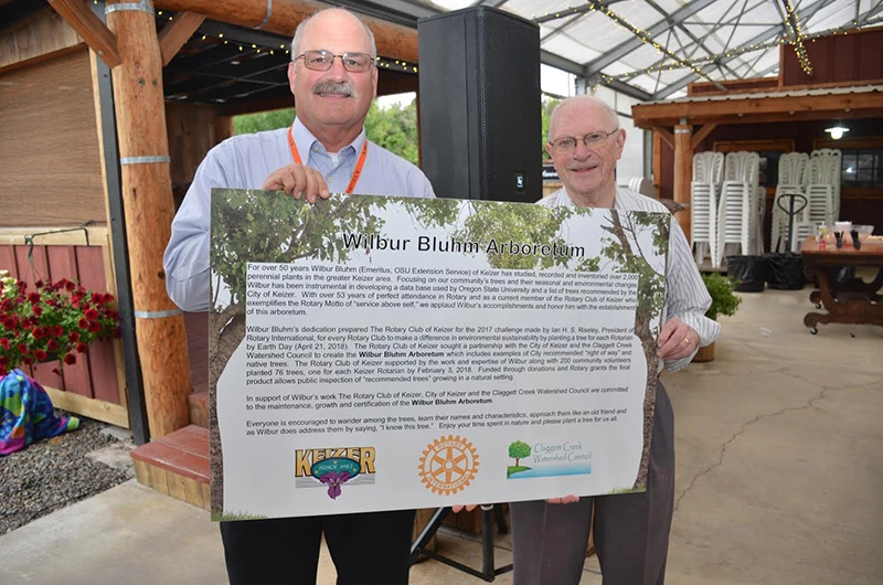 Wilbur Bluhm standing next to the Keizer Rotary Arboretum dedication sign